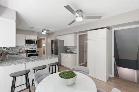 a kitchen with stainless steel appliances kitchen island granite countertop a refrigerator a sink a stove a dining table and chairs