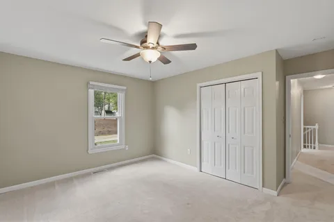 an empty room with windows and fan