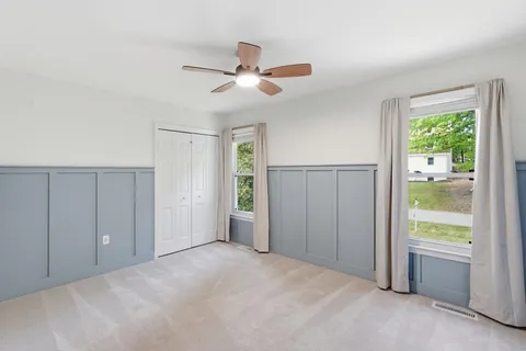 a view of a livingroom with a ceiling fan & windows