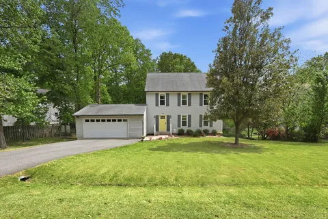 a view of a house with a big yard and large trees