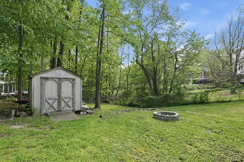 a view of backyard with a barn and large trees