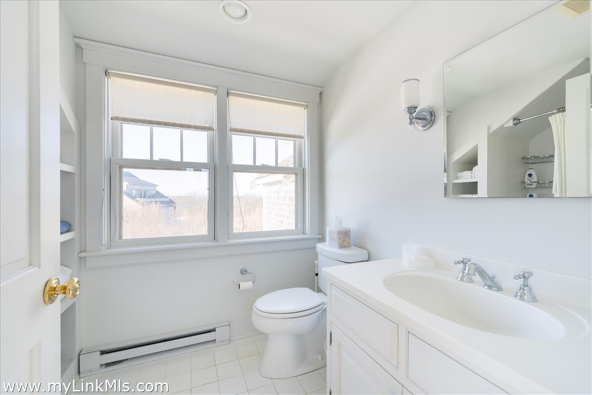 100 Baxter Road Nantucket, MA 02554 - Photo 10 of 11 a bathroom with a toilet sink and mirror next to a window