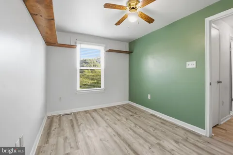 a view of an empty room with window and wooden floor