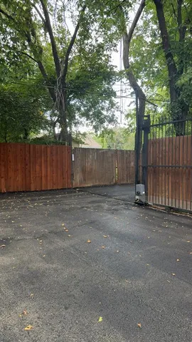 a view of a backyard with large trees and wooden fence