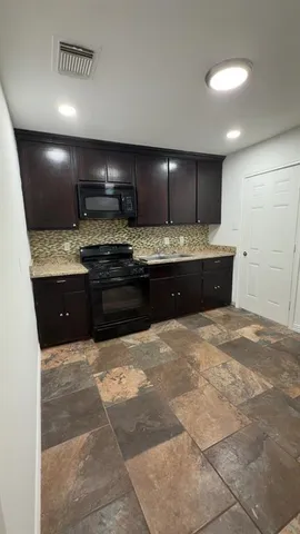 a large kitchen with kitchen island a sink stainless steel appliances and cabinets
