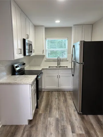 a kitchen with a sink a refrigerator a window and cabinets