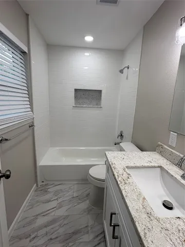 a bathroom with a granite countertop sink a toilet and bathtub