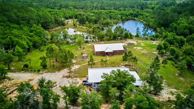 an aerial view of residential house with outdoor space and trees all around
