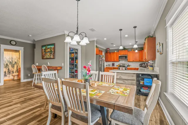 a view of a dining room and livingroom with furniture wooden floor a chandelier