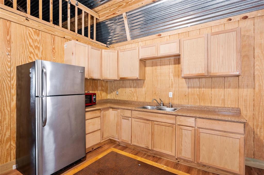 134 Maple Avenue Streetman, TX 75859 - Photo 8 of 19 Kitchen featuring light brown cabinetry, freestanding refrigerator, light wood-style flooring, light countertops, and wooden walls