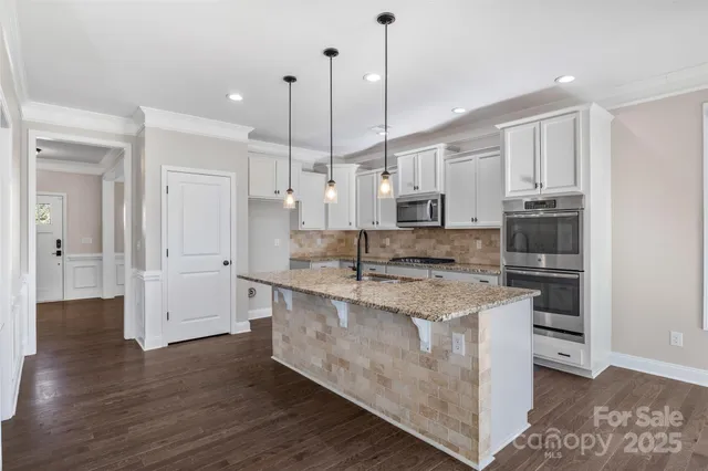 a large kitchen with stainless steel appliances granite countertop a stove and a wooden floors