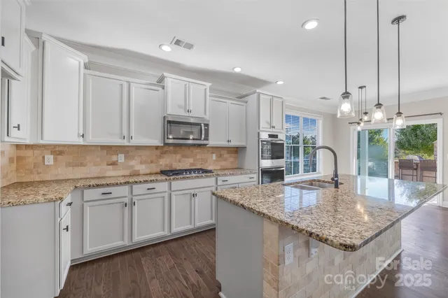 a kitchen with kitchen island granite countertop a sink a center island and cabinets