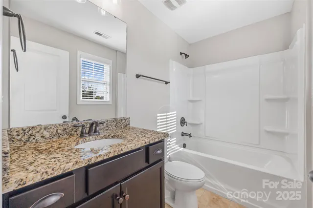 a bathroom with a granite countertop sink a toilet and bathtub