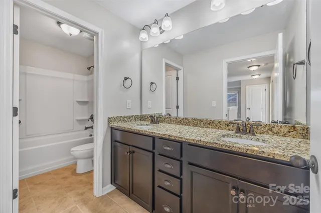 a bathroom with a granite countertop sink toilet a large mirror a bathtub and shower