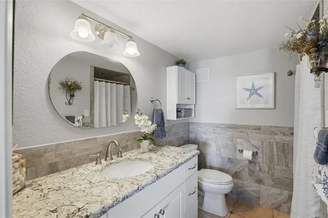 a bathroom with a granite countertop toilet a sink and a mirror