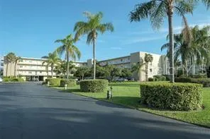 a front view of a house with a yard and palm trees