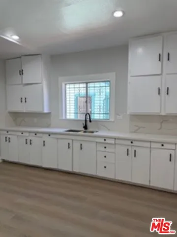 a large white kitchen with granite countertop a stove a sink and white cabinets