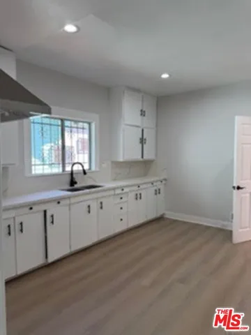 a large white kitchen with granite countertop white cabinets and a dishwasher
