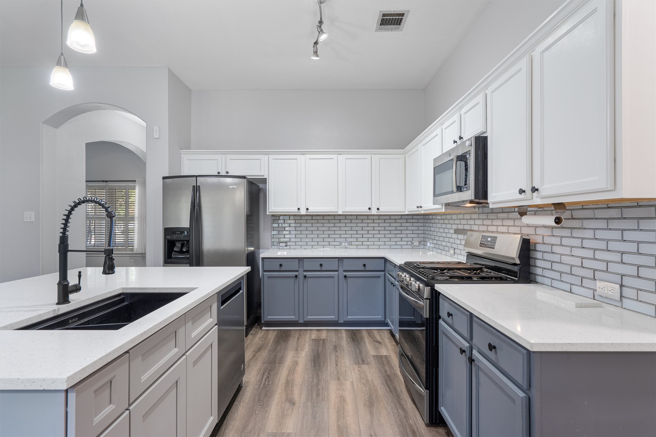 153 Hickory Lane Georgetown, TX 78633 - Photo 11 of 30 Modern kitchen featuring two-tone cabinetry, stainless steel appliances, light-toned countertops, and wood-finish flooring