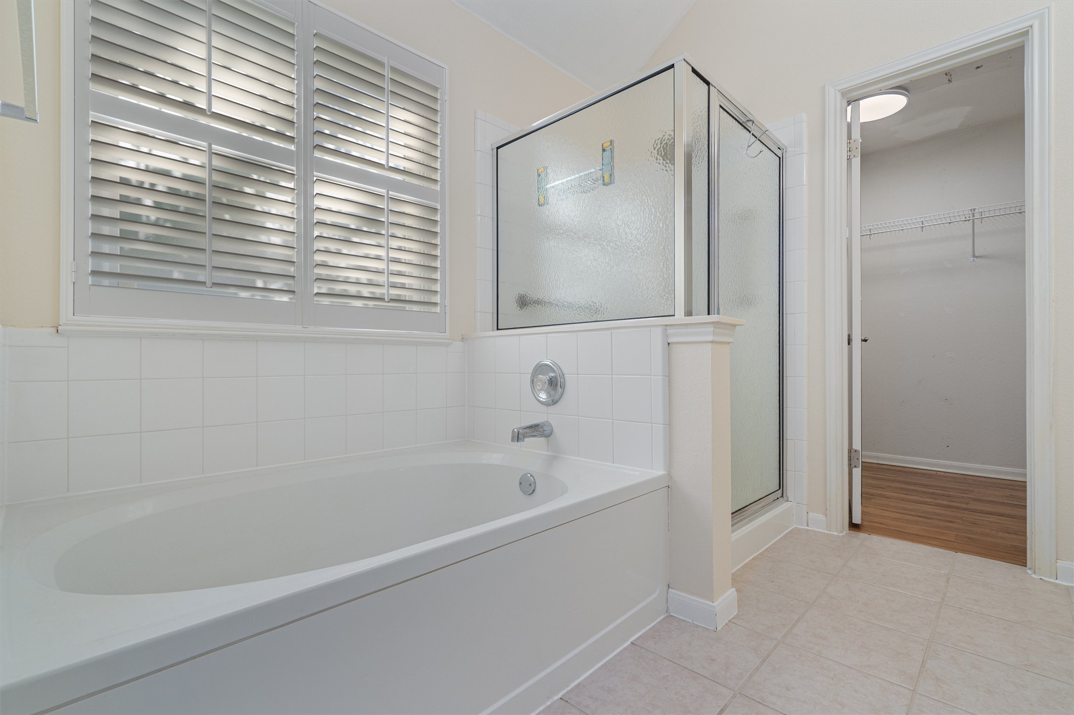 153 Hickory Lane Georgetown, TX 78633 - Photo 18 of 30 Bathroom featuring a built-in tub, white tile surround, and plantation shutters