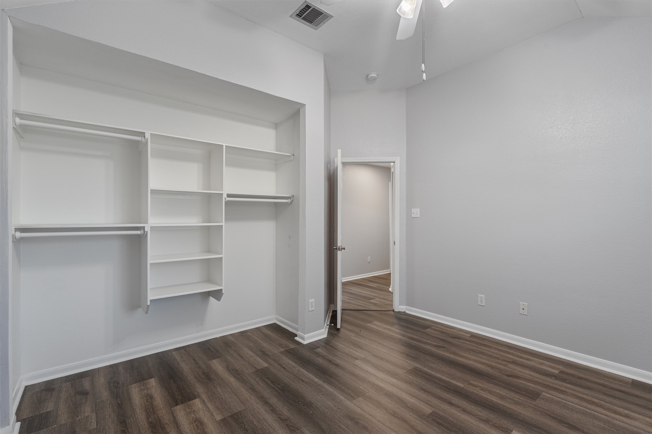 153 Hickory Lane Georgetown, TX 78633 - Photo 21 of 30 Bedroom featuring wood-finish flooring, built-in shelving, hanging rods, an overhead ceiling fan, and a light gray wall finish