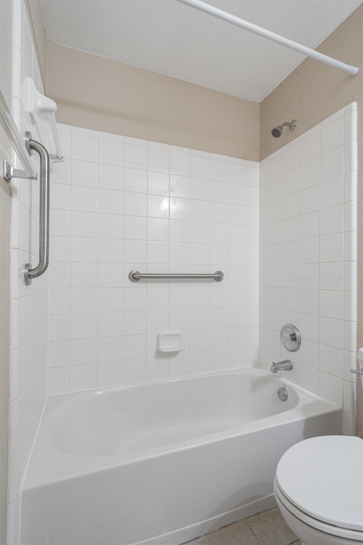 153 Hickory Lane Georgetown, TX 78633 - Photo 25 of 30 White tile surround bathtub with integrated grab bars, chrome fixtures, and a shower curtain rod