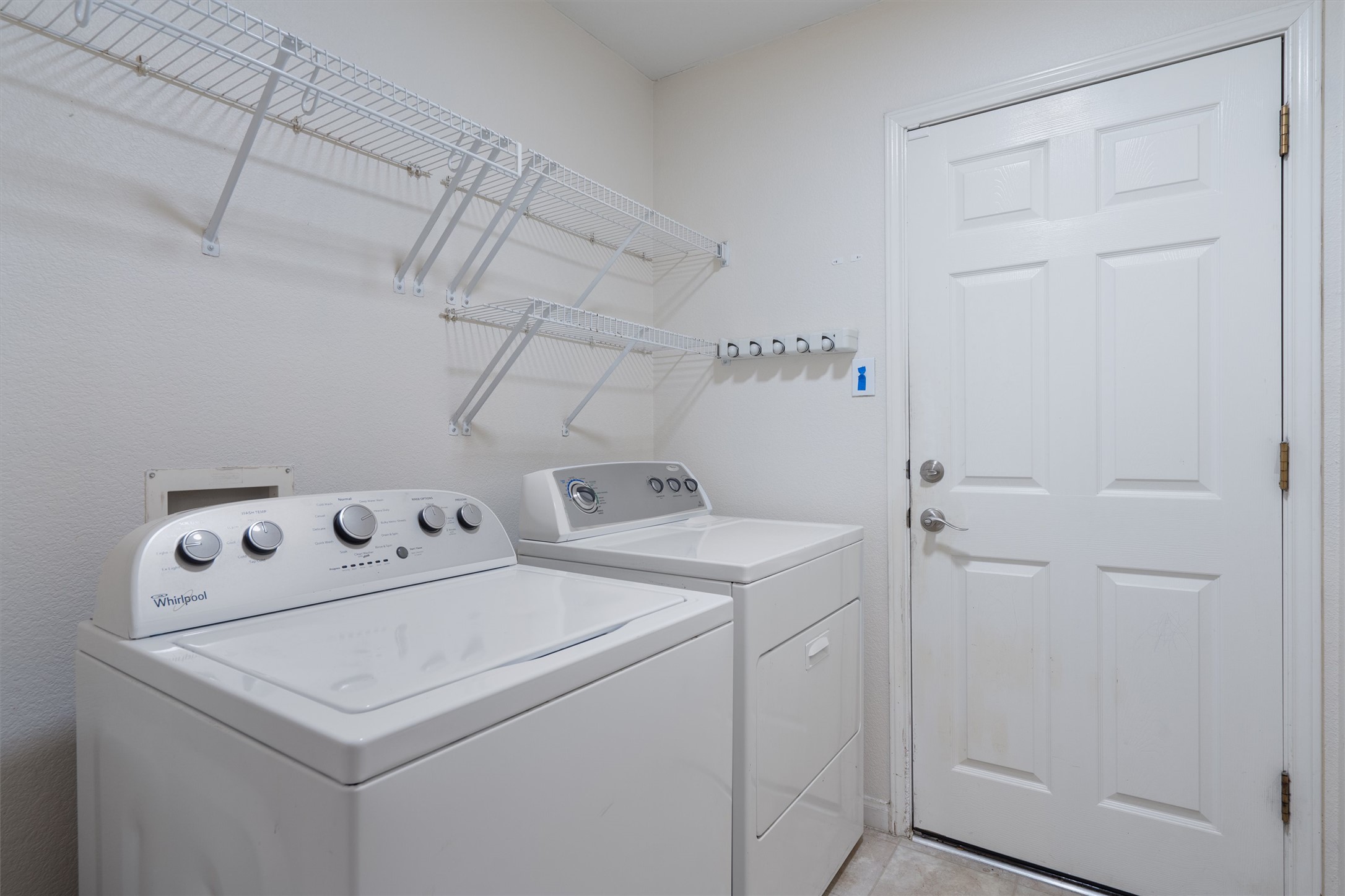 153 Hickory Lane Georgetown, TX 78633 - Photo 26 of 30 Dedicated laundry space featuring a white paneled door, built-in wire shelving, and light-toned flooring