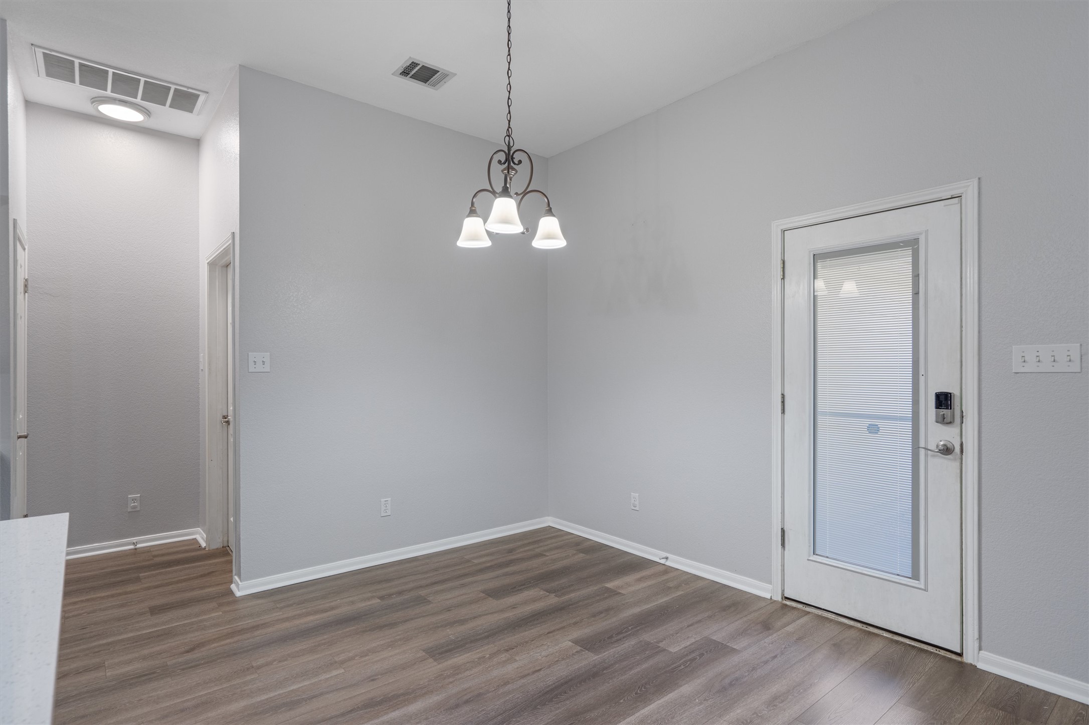153 Hickory Lane Georgetown, TX 78633 - Photo 9 of 30 Dining area featuring wood-finish flooring, a decorative chandelier, and a white paneled door with an integrated glass insert