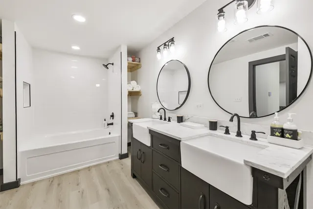 a bathroom with a double vanity sink mirror and bathtub