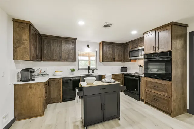 a kitchen with stainless steel appliances granite countertop a sink stove refrigerator and cabinets