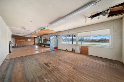 a view of a room with kitchen appliances and wooden floor