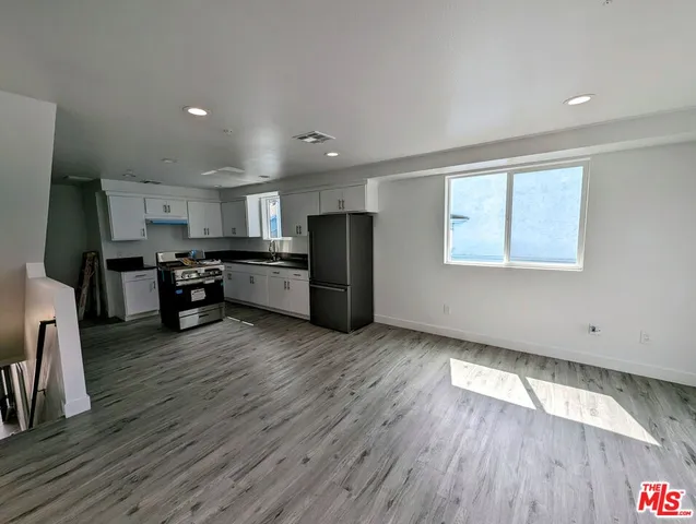 a living room with stainless steel appliances kitchen island granite countertop wooden floors and wooden cabinets