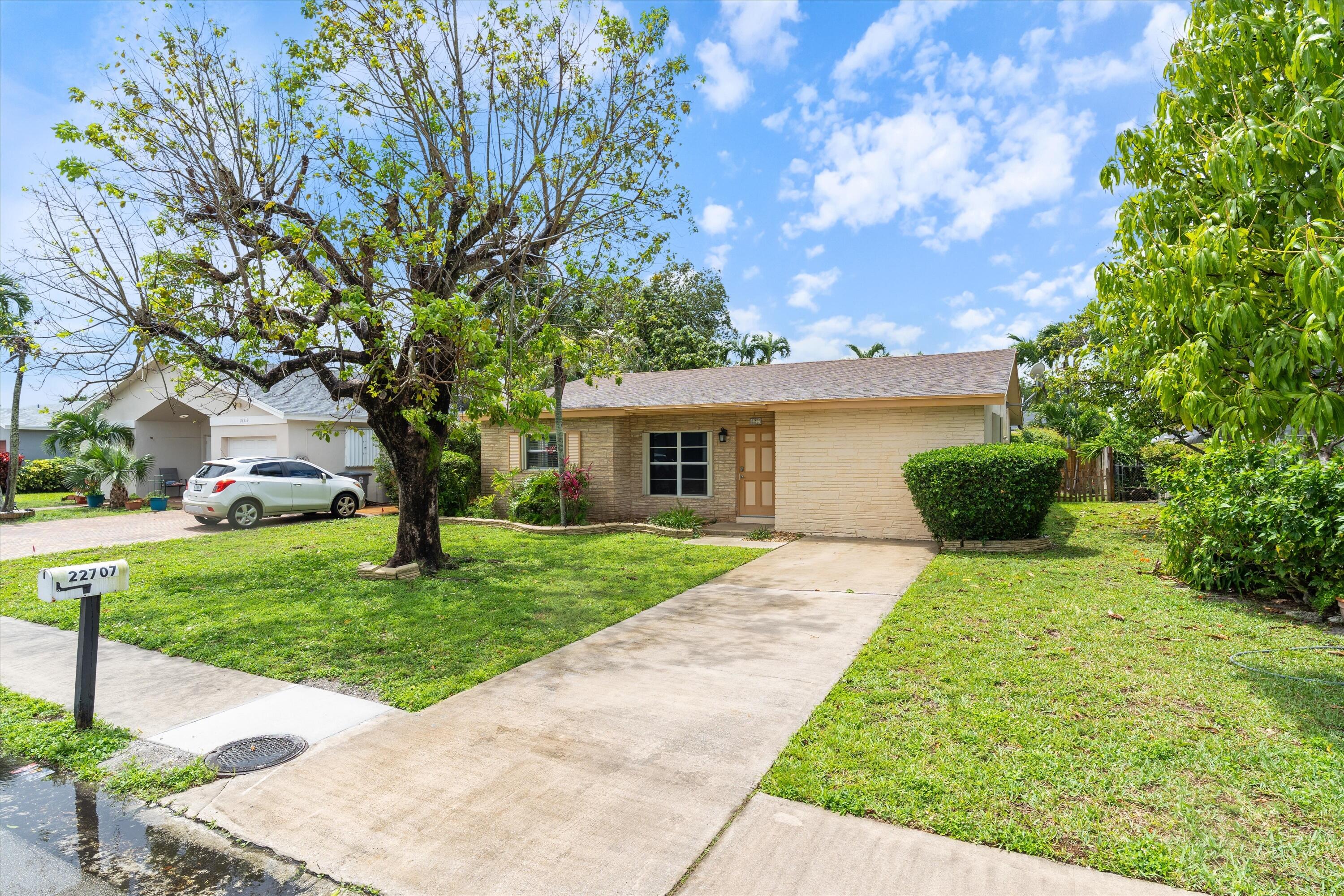 22707 Southwest 64th Way Boca Raton, FL 33428 - Photo 2 of 22 a front view of a house with a yard and a garden