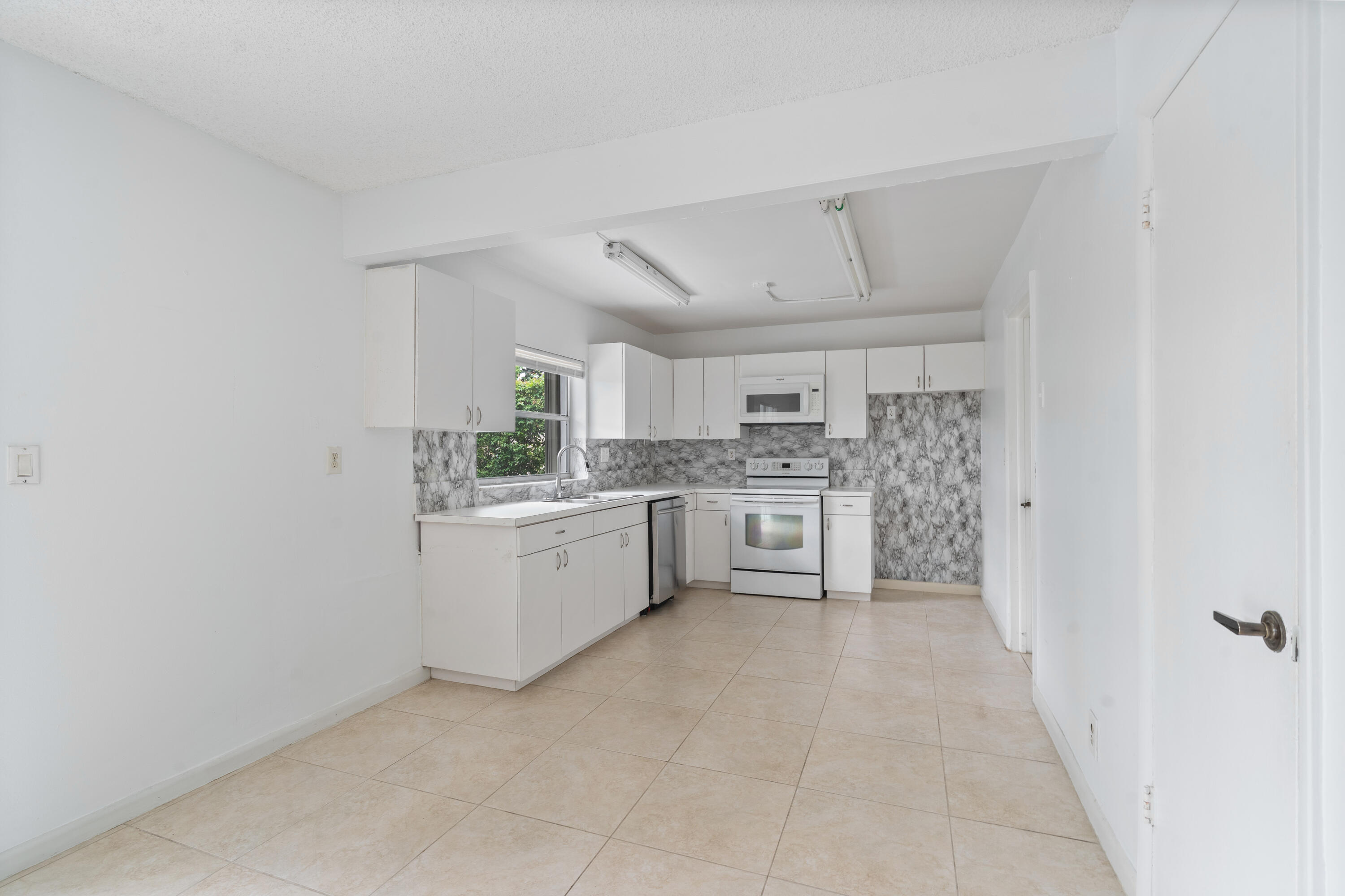 22707 Southwest 64th Way Boca Raton, FL 33428 - Photo 9 of 22 a kitchen with white cabinets and white appliances