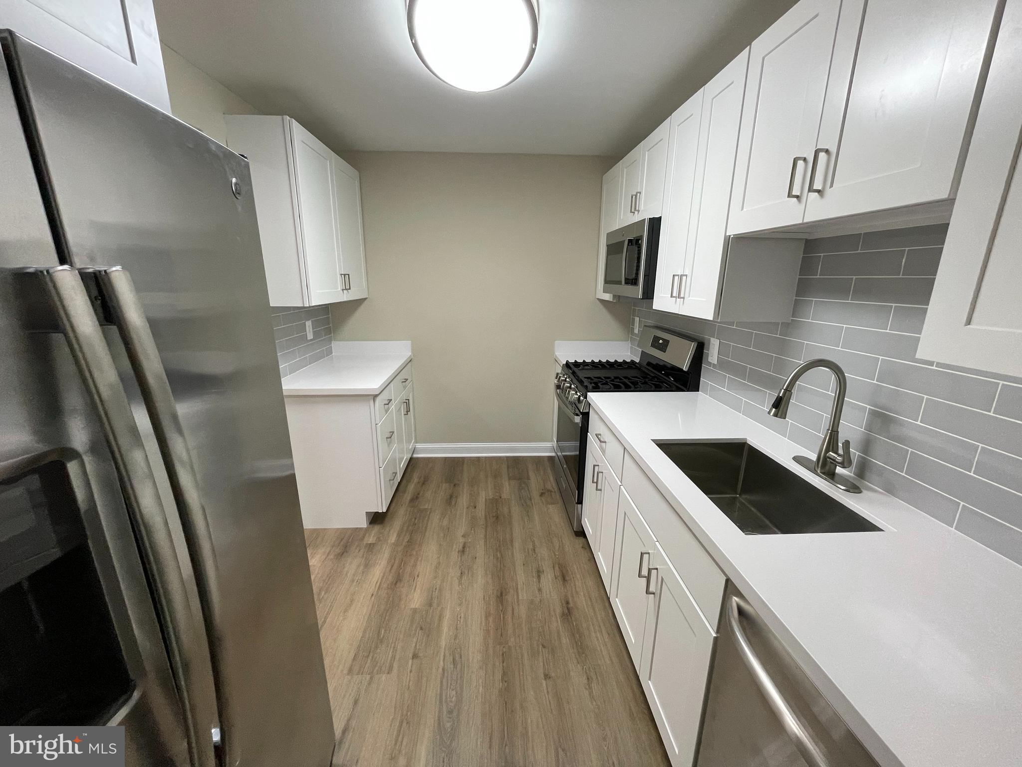 9220 Bridle Path Lane, Unit E Laurel, MD 20723 - Photo 4 of 14 a kitchen with a sink a refrigerator and cabinets