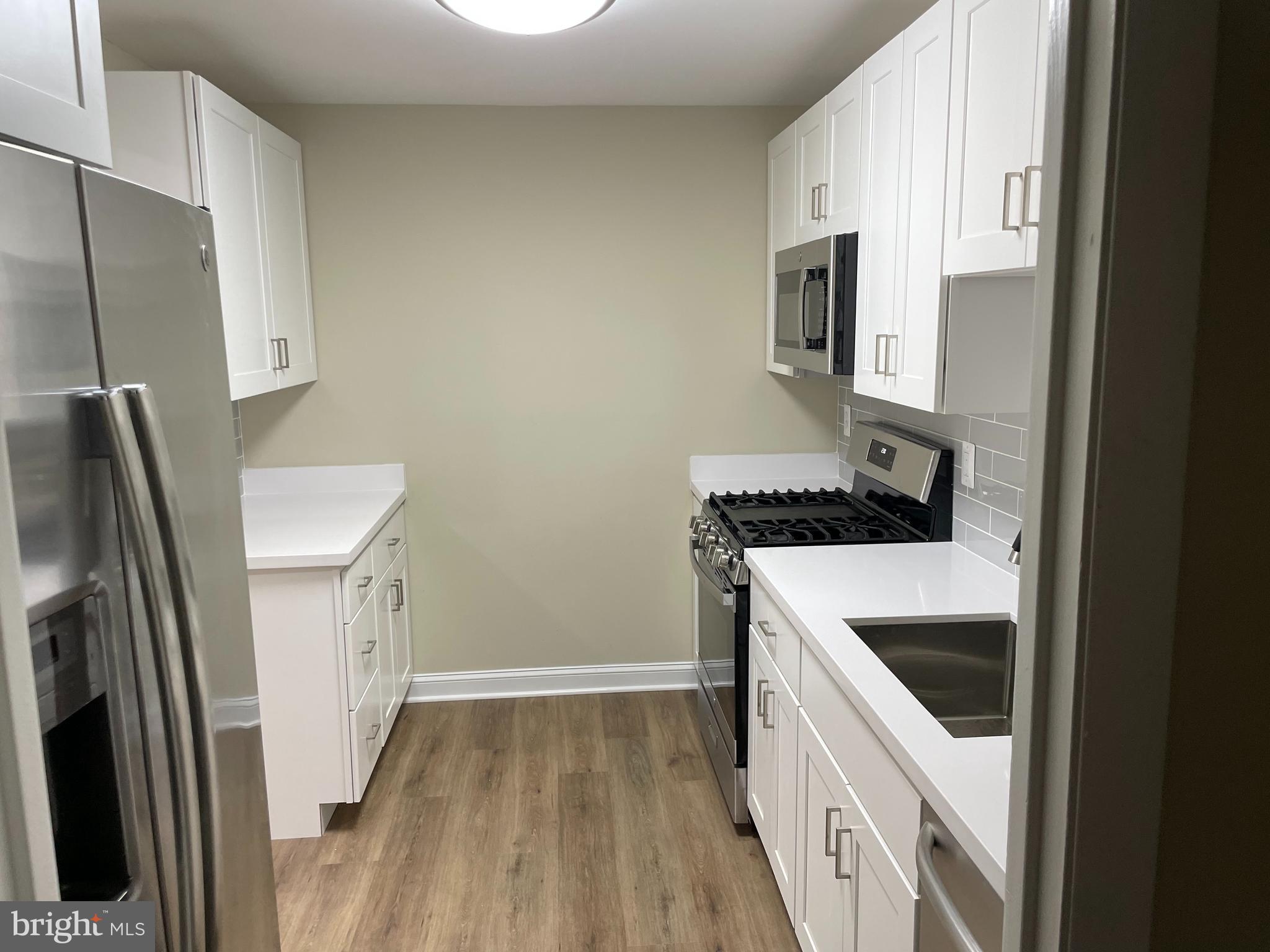 9220 Bridle Path Lane, Unit E Laurel, MD 20723 - Photo 5 of 14 a kitchen with a sink a refrigerator and a stove top oven