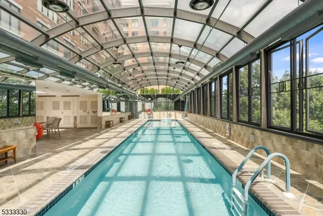 a view of swimming pool with a couches and lawn chairs with wooden floor