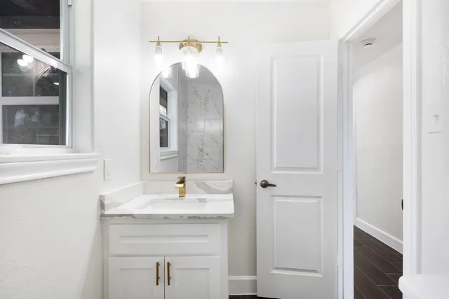 a bathroom with a granite countertop sink and a mirror