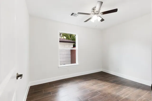 an empty room with a window and a ceiling fan
