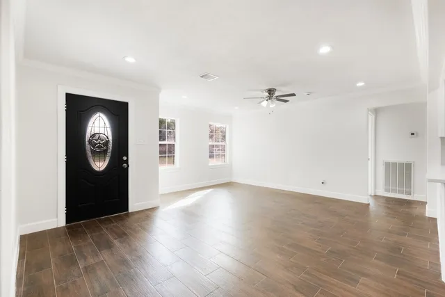 a view of an empty room with wooden floor and a window