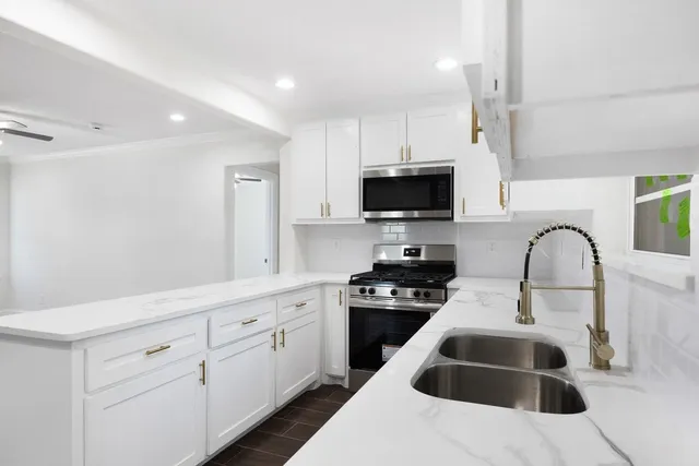 a kitchen with white cabinets and sink