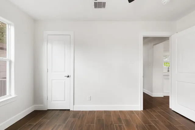an empty room with wooden floor and windows