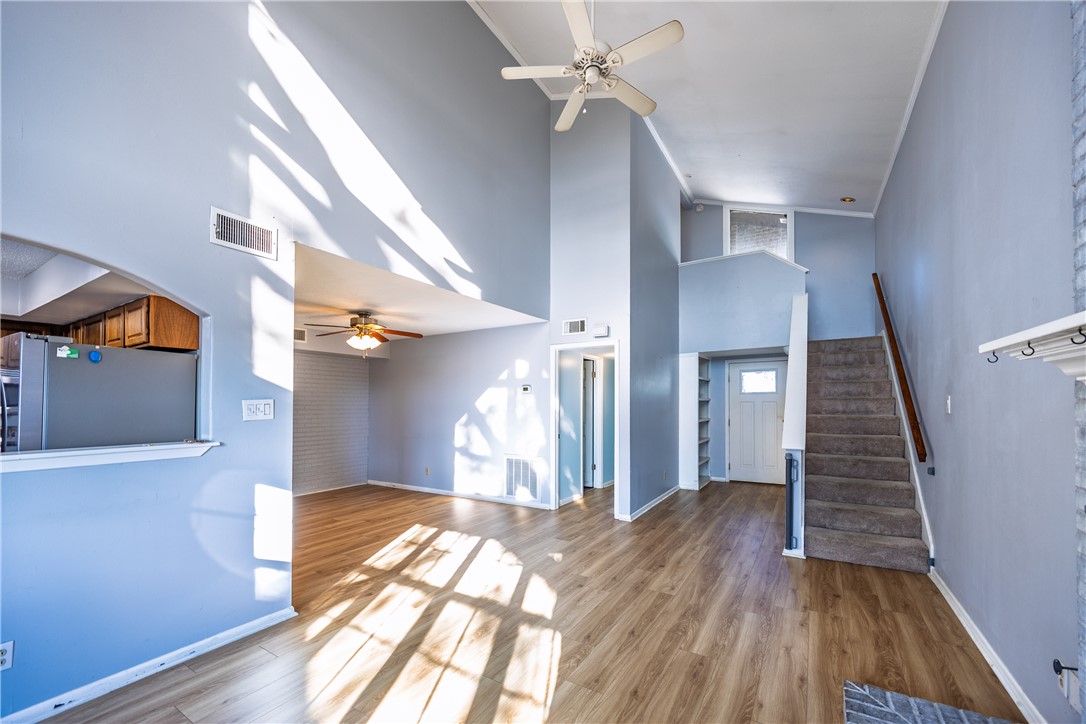 2002 South Lubbock Street Brenham, TX 77833 - Photo 9 of 26 Unfurnished living room with a ceiling fan, a towering ceiling, stairs, and wood finished floors