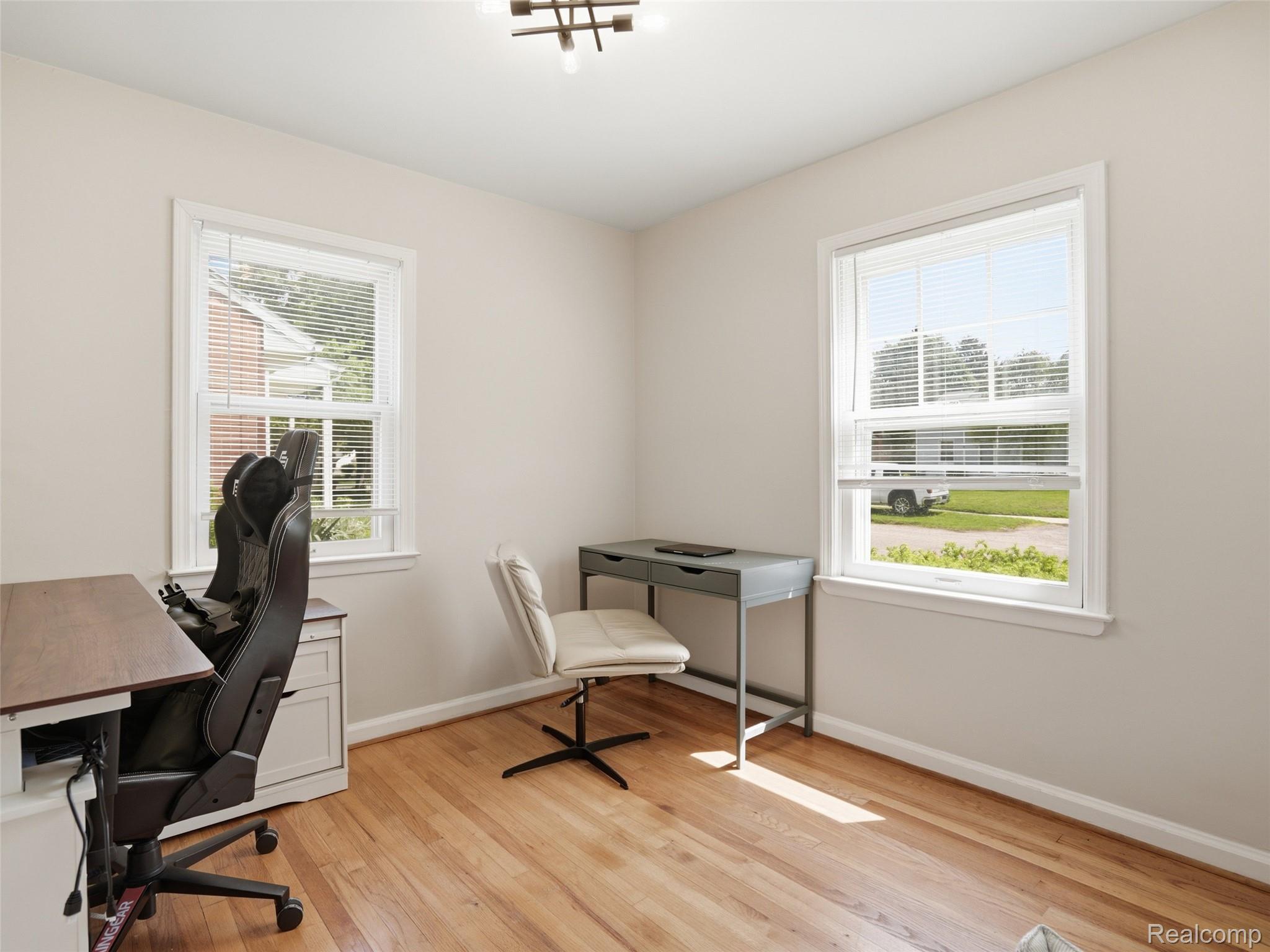 320 South Avery Road Waterford, MI 48328 - Photo 19 of 25 Light-filled room featuring wood-finish flooring, neutral wall tones, two double-hung windows with blinds, and a contemporary ceiling light fixture
