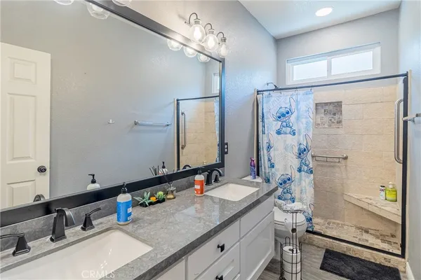 a bathroom with a granite countertop sink a mirror and a shower