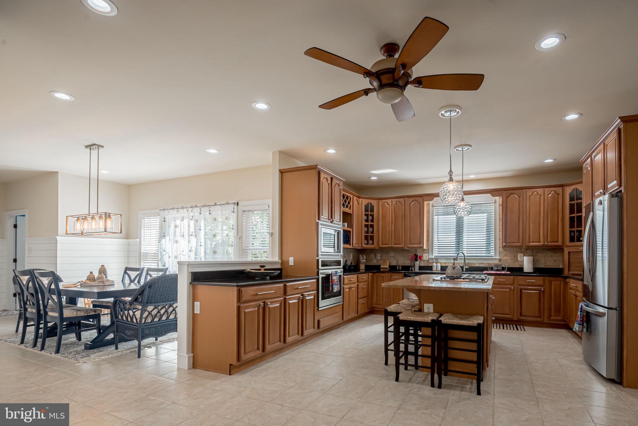 125 Cornwall Road Rehoboth Beach, DE 19971 - Photo 14 of 52 a kitchen with stainless steel appliances kitchen island granite countertop a refrigerator a stove a sink a dining table and chairs with wooden floor