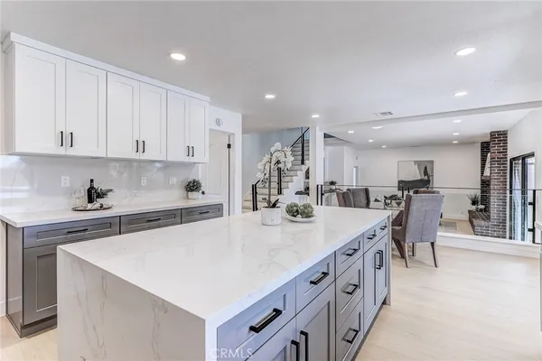 a dining hall with stainless steel appliances kitchen island granite countertop a refrigerator and a sink