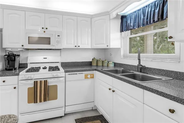 a kitchen with granite countertop a sink a stove and cabinets