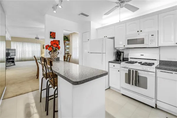 a kitchen with stainless steel appliances granite countertop a stove a refrigerator and a refrigerator with white cabinets