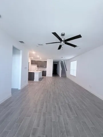 a view of a livingroom with a ceiling fan & wooden floor